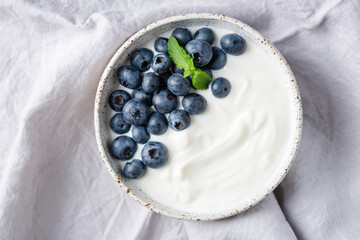 Bowl of plain greek yogurt topped with fresh blueberries. Healthy meal rich in proteins, antioxidants and calcium
