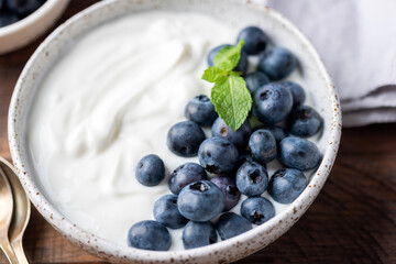 Bowl of plain greek yogurt topped with fresh blueberries. Healthy meal rich in proteins, antioxidants and calcium