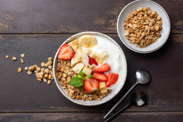 Healthy diet fitness meal: bowl of plain greek yogurt, topping granola strawberries banana