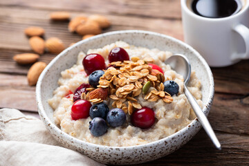 Healthy breakfast meal: oatmeal porridge with cranberries, blueberries and crunchy nutty granola topping