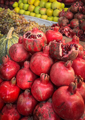 Fresh pomegranates on market stall. Vibrant red fruits displayed for sale at local farmers market. Healthy food and organic produce concept.