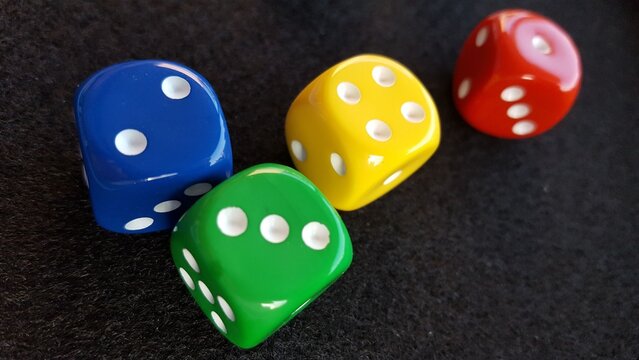 Vier bunte W&uuml;rfel auf einem schwarzen Tisch