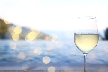 a glass of white wine, a background under the summer sun, a bokeh and sun glare, a blurred abstract background