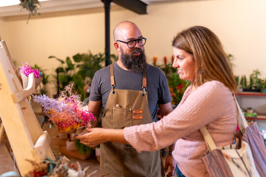Florist helping customer choosing dried flower arrangement