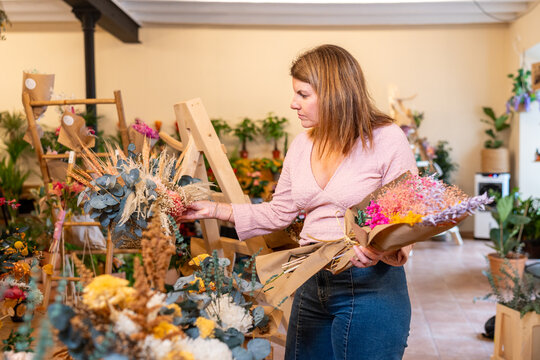 Customer exploring floral shop and holding dried bouquet - Powered by Adobe