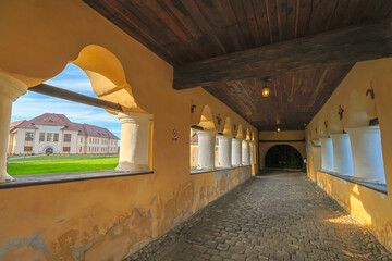 Historic courtyard of Prejmer fortified church in Transylvania, Romania, showing medieval defensive walls, arched entrance and cobblestone houses. UNESCO site of Romania