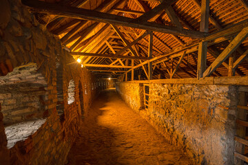 Prejmer Fortified church defensive wall passage in ancient stone construction, wooden beams, illuminated by dim lights creating an old and historic atmosphere. UNESCO site of Romania in Transylvania.