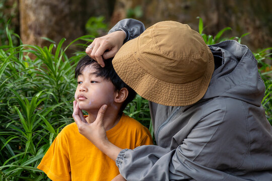 A mother applying sunscreen lotion to her sons face before outdoor activities