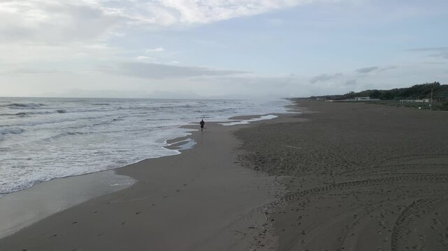 drone, vista su uomo che corre sulla spiaggia (jogging)
