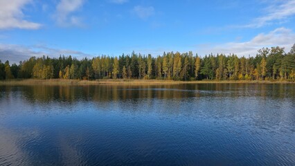 Scenic view of tranquil lake surrounded by autumn trees reflecting in the water under a clear blue sky