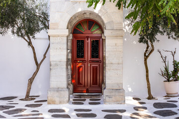 white building with red door and vegetation. Greek island architectural design. atmospheric cityscape. ornamental entrance with red door. white architecture