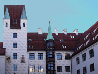Old Town Hall of Munich with patterned white walls, red roof, turrets and bay window, neat geometric facade, fresh clear sky, minimalistic urban style