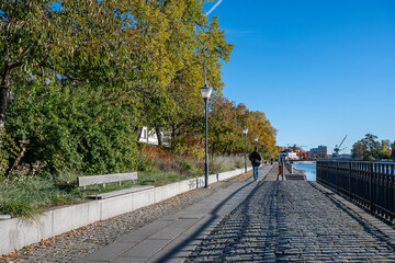 Unrecognizable people walk along Motala Stream and Norrköping waterfront Saltängen during autumn. Norrköping is a historic industrial town in Sweden.