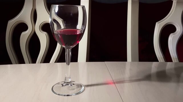 Drinking and driving concept. Car key on a white table and hand with wine glass in dark room