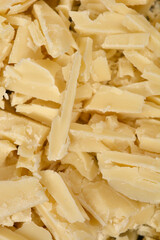A large pile of irregular white chocolate shavings and pieces fills the entire frame, creating a rich and varied texture