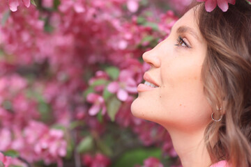 Fototapeta premium Springtime background, a woman in pink in a blooming cherry orchard, a model posing in a romantic style