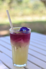 Refreshing butterfly pea lemonade drink on white table outdoor.