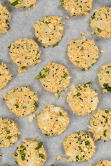 Raw vegan patties, made primarily from chopped soybeans, onions, and herbs, are arranged on a parchment-lined baking sheet, ready for cooking
