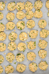 Raw vegan patties, made primarily from chopped soybeans, onions, and herbs, are arranged on a parchment-lined baking sheet, ready for cooking