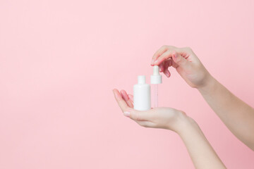 Hands hold glass unbranded bottle with serum or essential oil with pipette. Concept of beauty. Product cosmetic advertising
