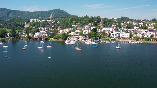 Aerial of beautiful resort town Gmunden on mountain Lake Traunsee, Salzkammergut. Serene lake, high Alp mountain, boats and picturesque buildings along the shoreline. Austria tourism and scenic places