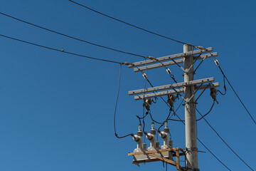 Top of a power pole with wires and cables against a blue sky