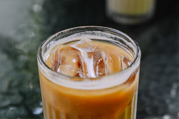 Iced coffee latte with layers of espresso, milk, and ice on a dark table, a refreshing and cool beverage