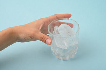 氷の入ったグラスを持つ女性の手