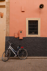 Exterior of a Moroccan-style house in warm brown tones with a bicycle leaning against the wall, combining simplicity and urban charm.