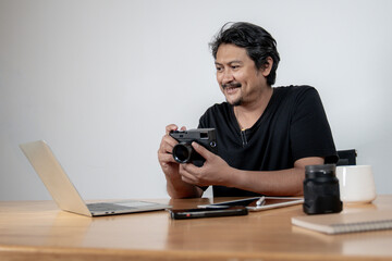 A young male photographer working on photo editing at his home studio, representing creativity,...