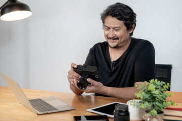 A young male photographer working on photo editing at his home studio, representing creativity,...