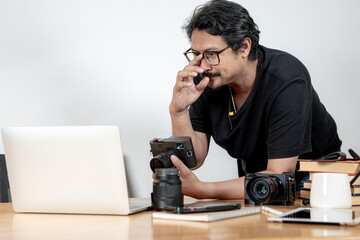 A young male photographer working on photo editing at his home studio, representing creativity,...