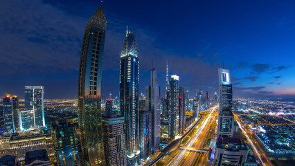 Fototapeta premium Dubai downtown architecture day to night timelapse. Top view over Sheikh Zayed road with illuminated skyscrapers and traffic.
