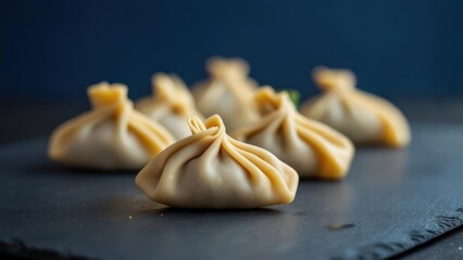Delicate Georgian khinkali dumplings artfully arranged on a dark slate surface, ready to be savored, evoking warmth and culinary delight.
