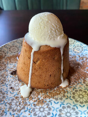 Rum baba decorated with whipped cream. Easter cake on the ceramic plate.  Fondant with white vanilla ice cream and chocolate. Food background, hot dessert.