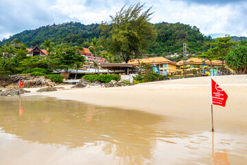 Patong Beach Phuket with red flag turquoise blue water Thailand.