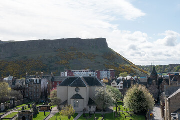 The Kirk of the Canongate in Edinburgh with surrounding historical buildings and hills.