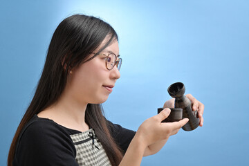 徳利から酒を注ぐ若い日本人女性