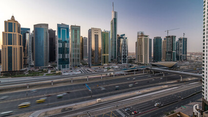 Fototapeta premium Aerial view of Jumeirah lakes towers skyscrapers night to day timelapse with traffic on sheikh zayed road.