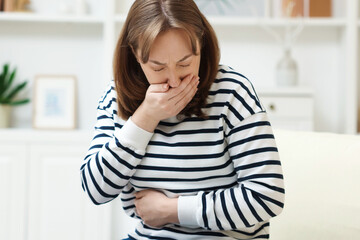 Fototapeta premium Woman suffering from stomach ache and nausea at home