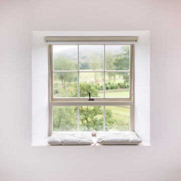 Sash window with cushions overlooking countryside in UK home