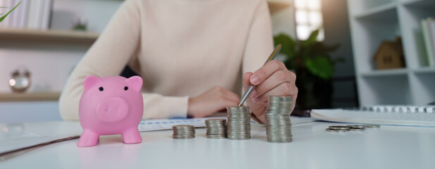 Financial planning. Woman organizing coins and piggy bank while reviewing financial documents.
