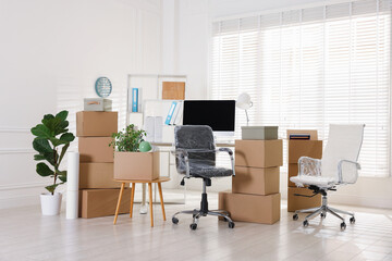 Moving day. Cardboard boxes, computer and furniture in office