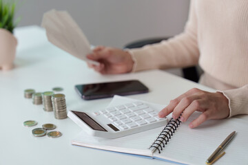 Financial Planning. Woman calculating expenses with a calculator and cash.