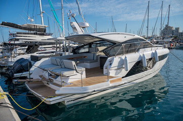 A sleek white yacht docked at the marina, featuring an open deck area with comfortable seating and modern design details at Limassol Marina