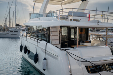 A sleek and modern yacht docked peacefully at the marina, showcasing its elegant design and spacious upper deck at Limassol Marina