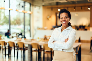 African-American Woman Smiling in Bright Office Café With Arms Crossed, Professional and Confident