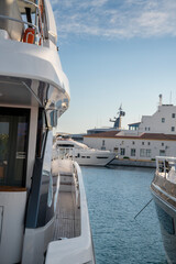 A sleek yacht’s side deck with polished chrome railings and teak wood flooring, docked peacefully in a marina under clear blue skies at Limassol Marina
