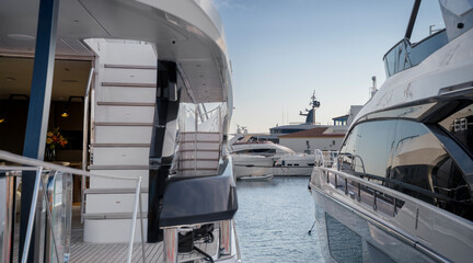 Two modern yachts docked side by side in a calm marina, with stairs leading to upper decks and glass railings at Limassol Marina.