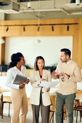 African-American Woman, Asian Woman, and Man Collaborate in Business Meeting at Modern Office